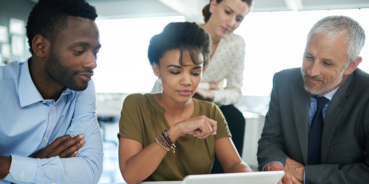 Four workers looking at a computer screen